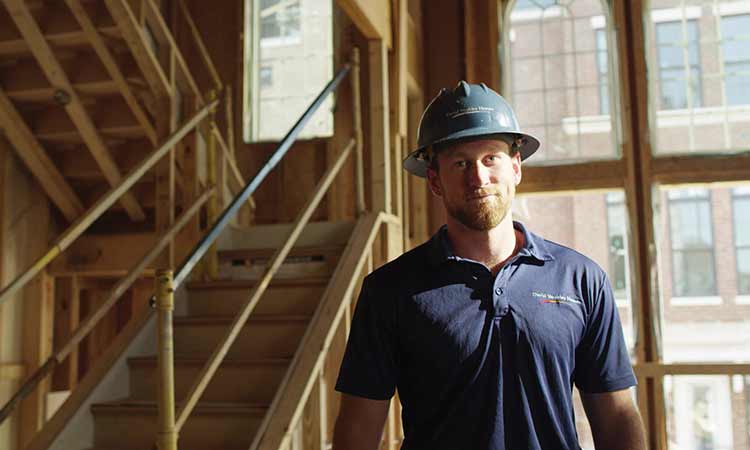 a man wearing a David Weekley Homes hardhat standing in a home under construction