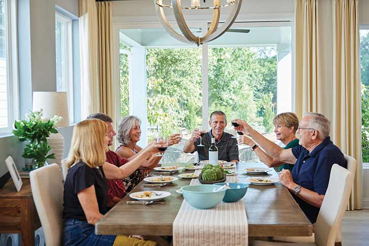 Encore by David Weekley Homes homeowners sitting a dining table and raising glasses of wine for a toast