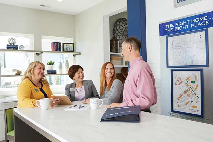 A David Weekley Homes Sales Consultant sitting at a counter with a customer and real estate agent
