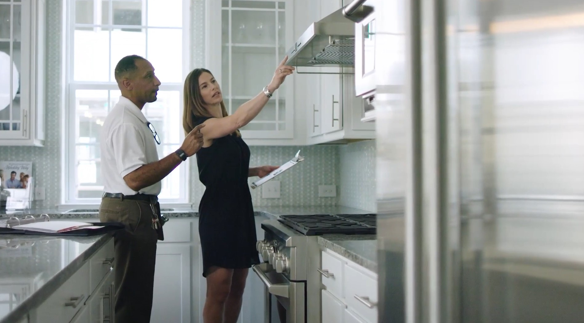 A David Weekley Homes Sales Consultant shows a customer the details of an oven hood in a kitchen