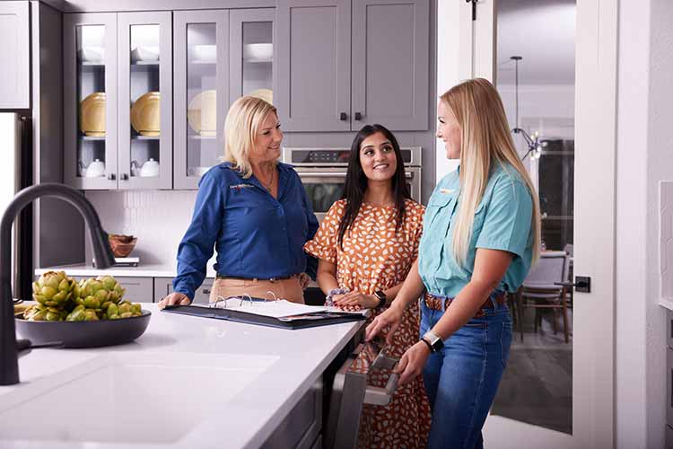 A David Weekley Homes Warranty Representative talks with a customer and Sales Consultant in a kitchen